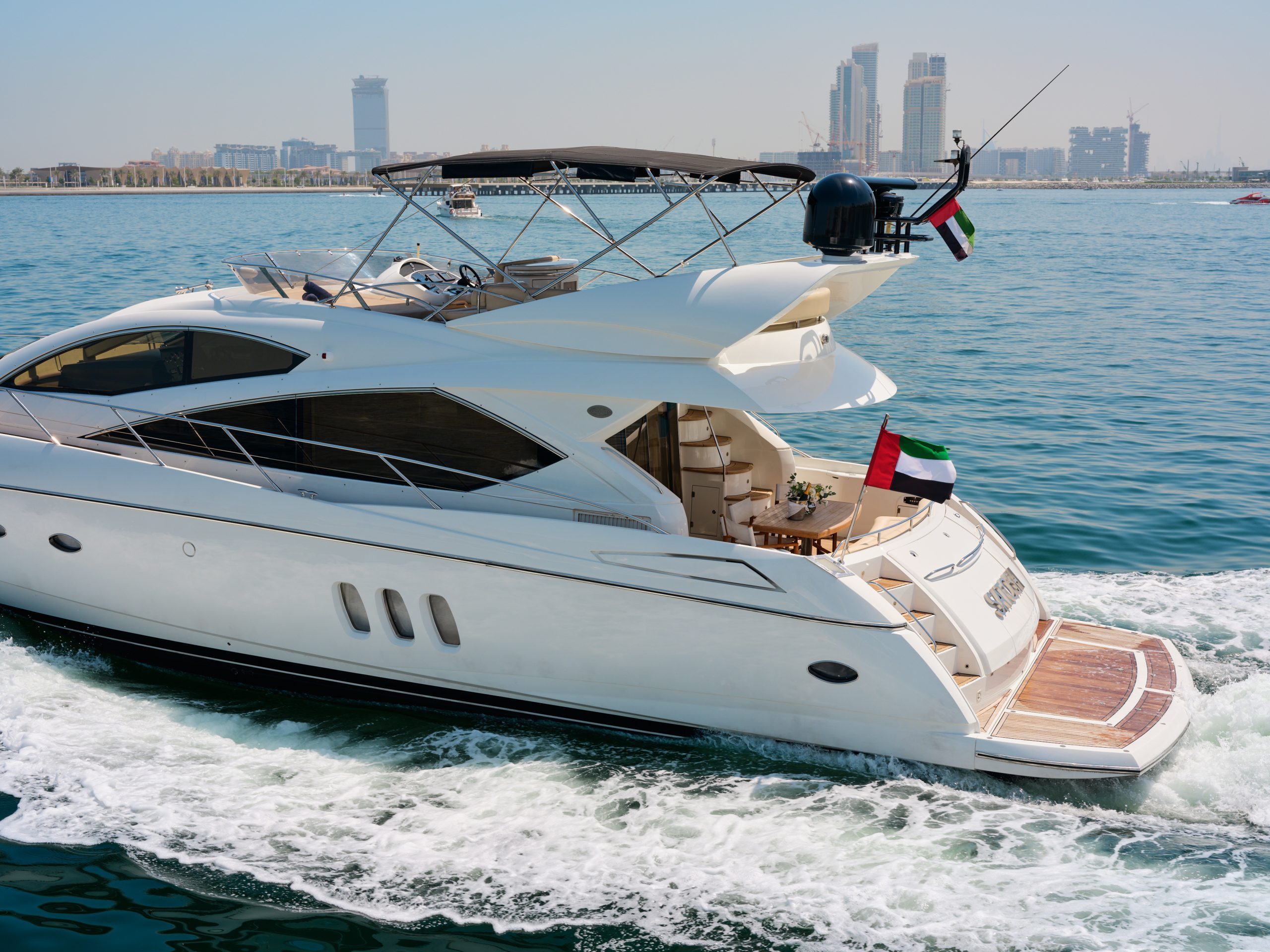 Sunseeker Satoshi 70 luxury yacht cruising at speed in Dubai with skyline in the background