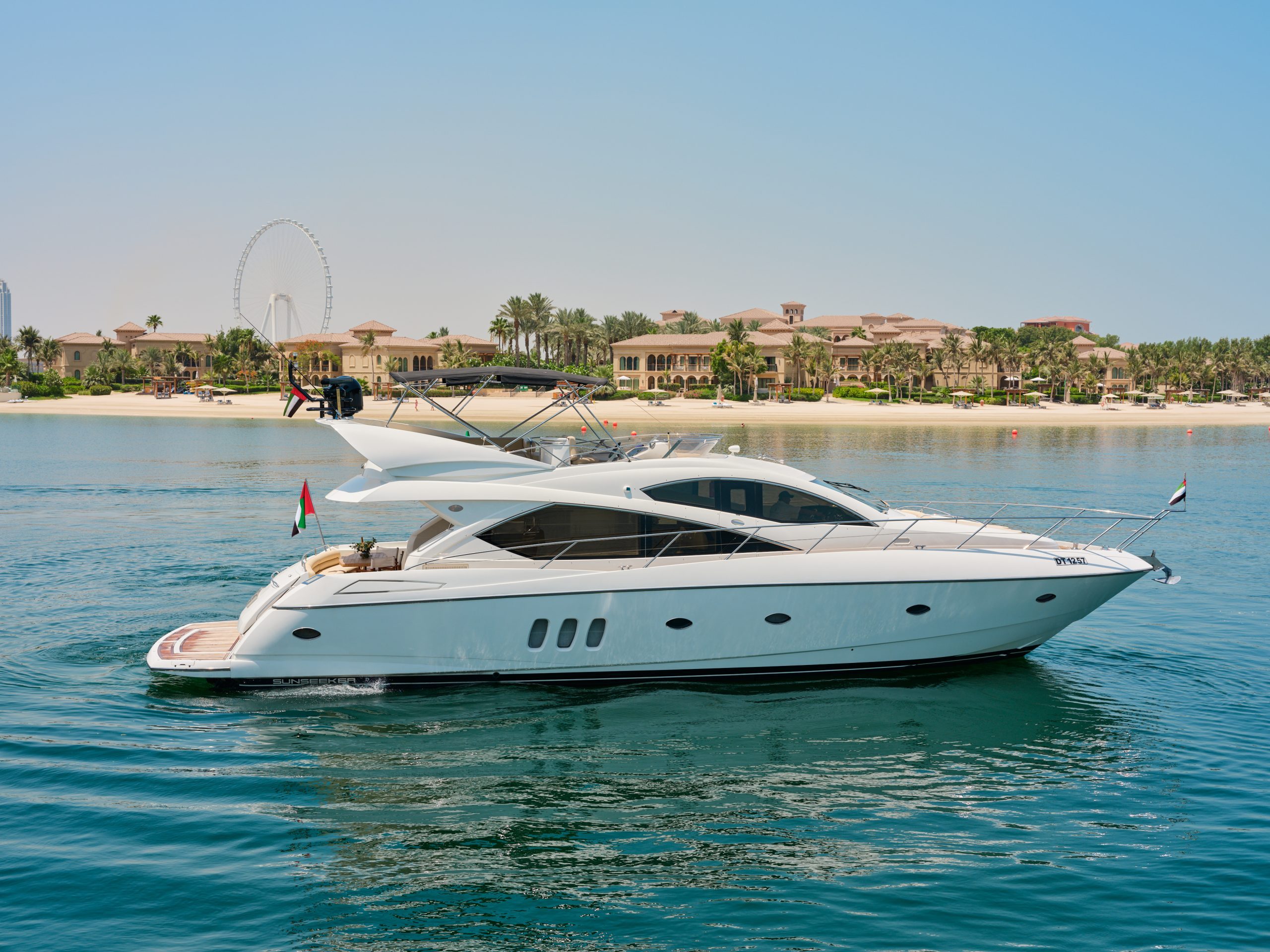 Side profile of Sunseeker Satoshi 70 motor yacht anchored on calm turquoise waters in Dubai