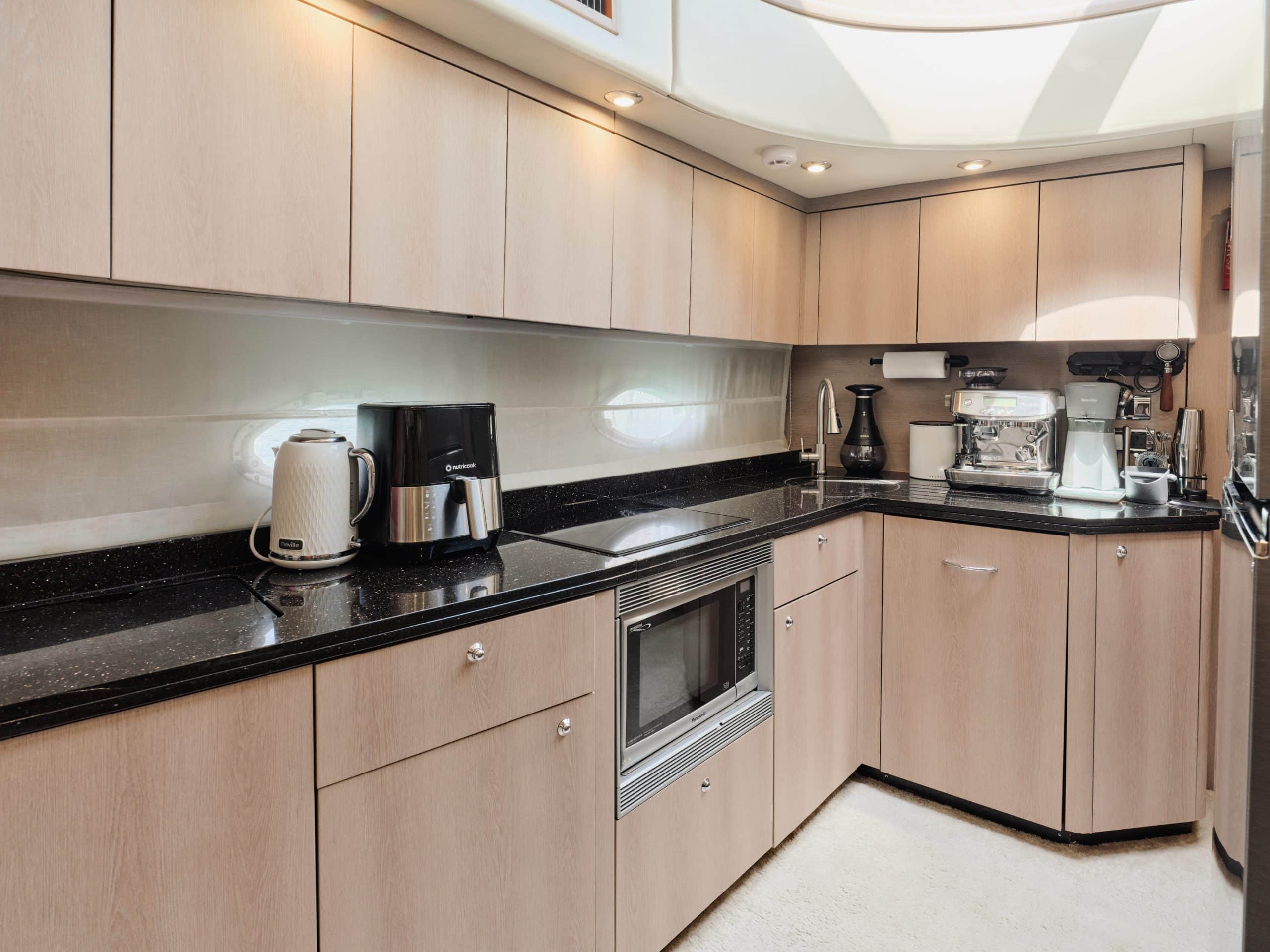 Sunseeker Satoshi 70 yacht galley kitchen with modern appliances and wooden cabinetry