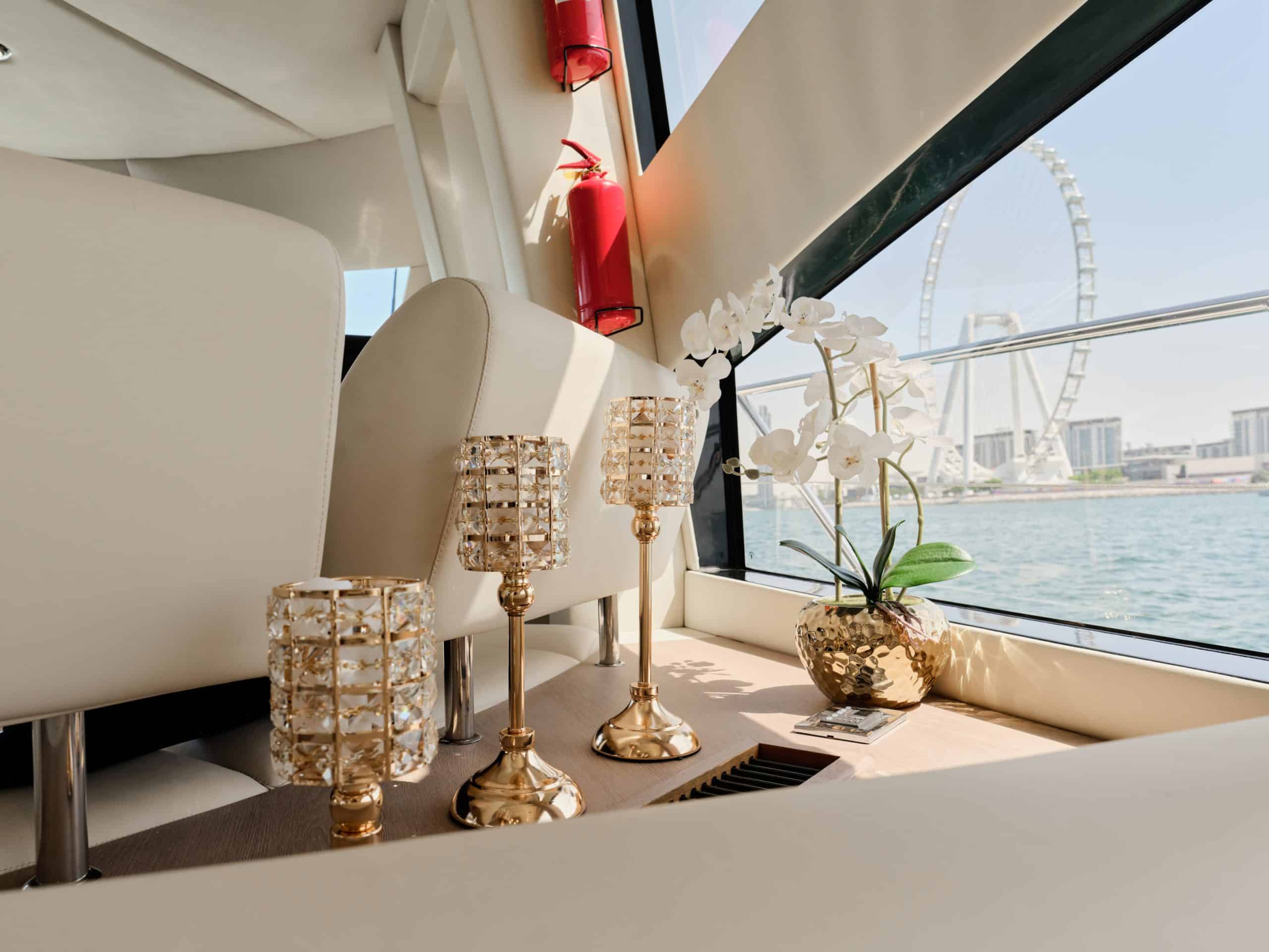 Luxury yacht interior window view with decorative orchid and gold candle holders overlooking Dubai Marina