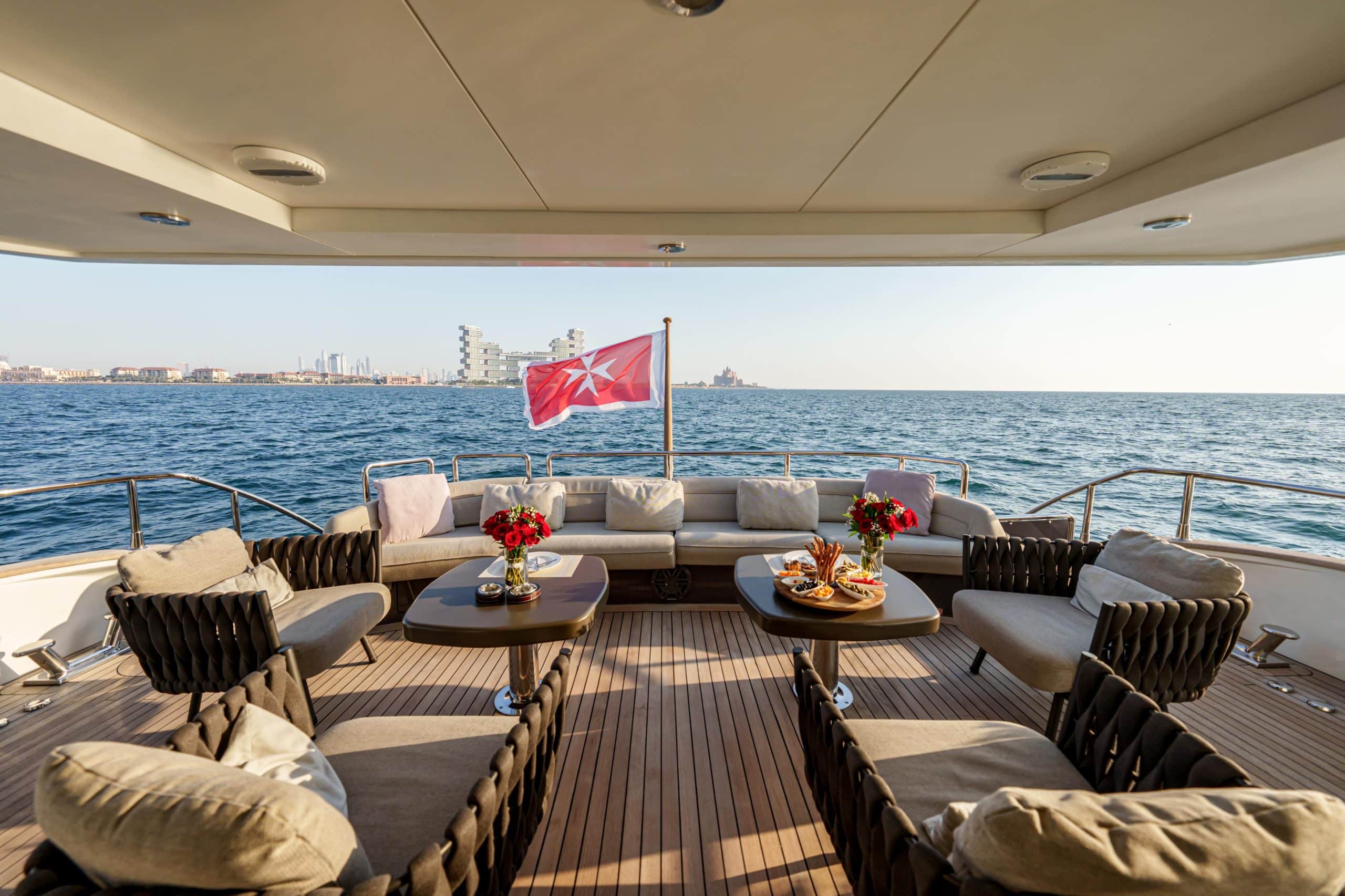 Tatti 110 yacht aft deck lounge with dining table and marina views