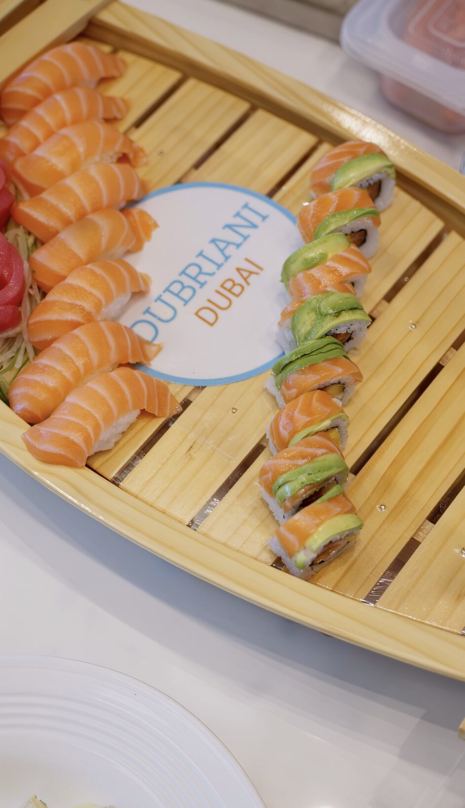 Assorted sushi rolls and salmon sashimi served on a wooden board aboard a luxury yacht in Dubai