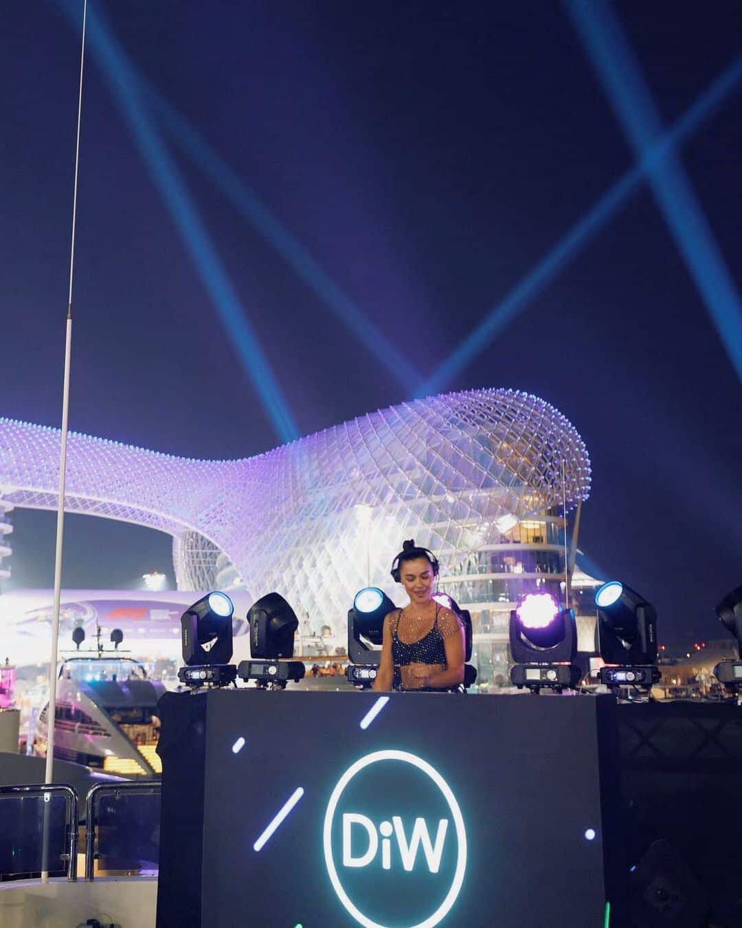 Live DJ performing at luxury outdoor waterfront event with stage lighting