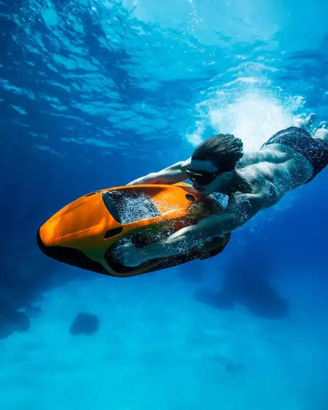 Rider using an orange Seabob underwater in clear blue sea