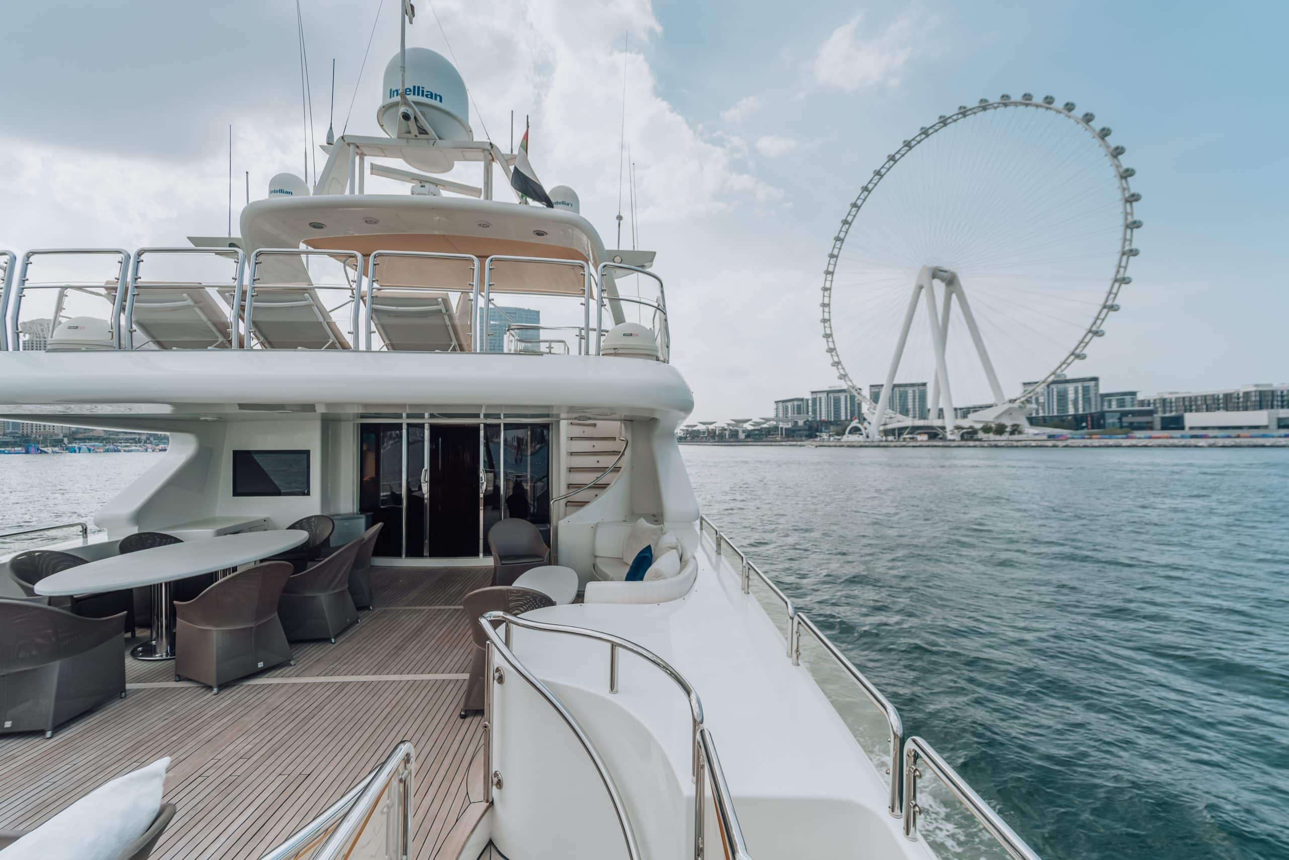 Luxury yacht deck near waterfront Ferris wheel.