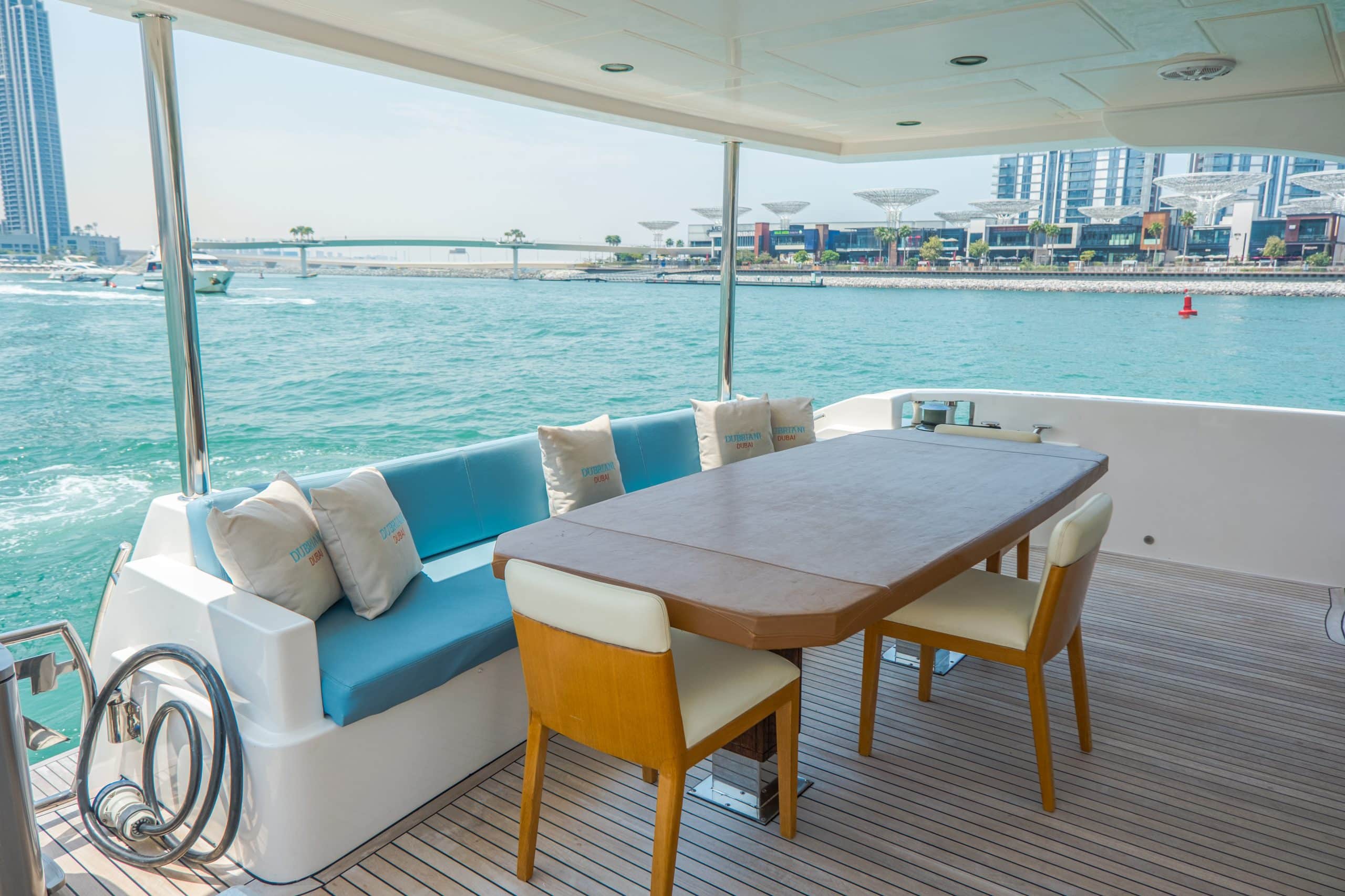 Cabo 77 yacht indoor dining area with wooden table and ocean view in Dubai