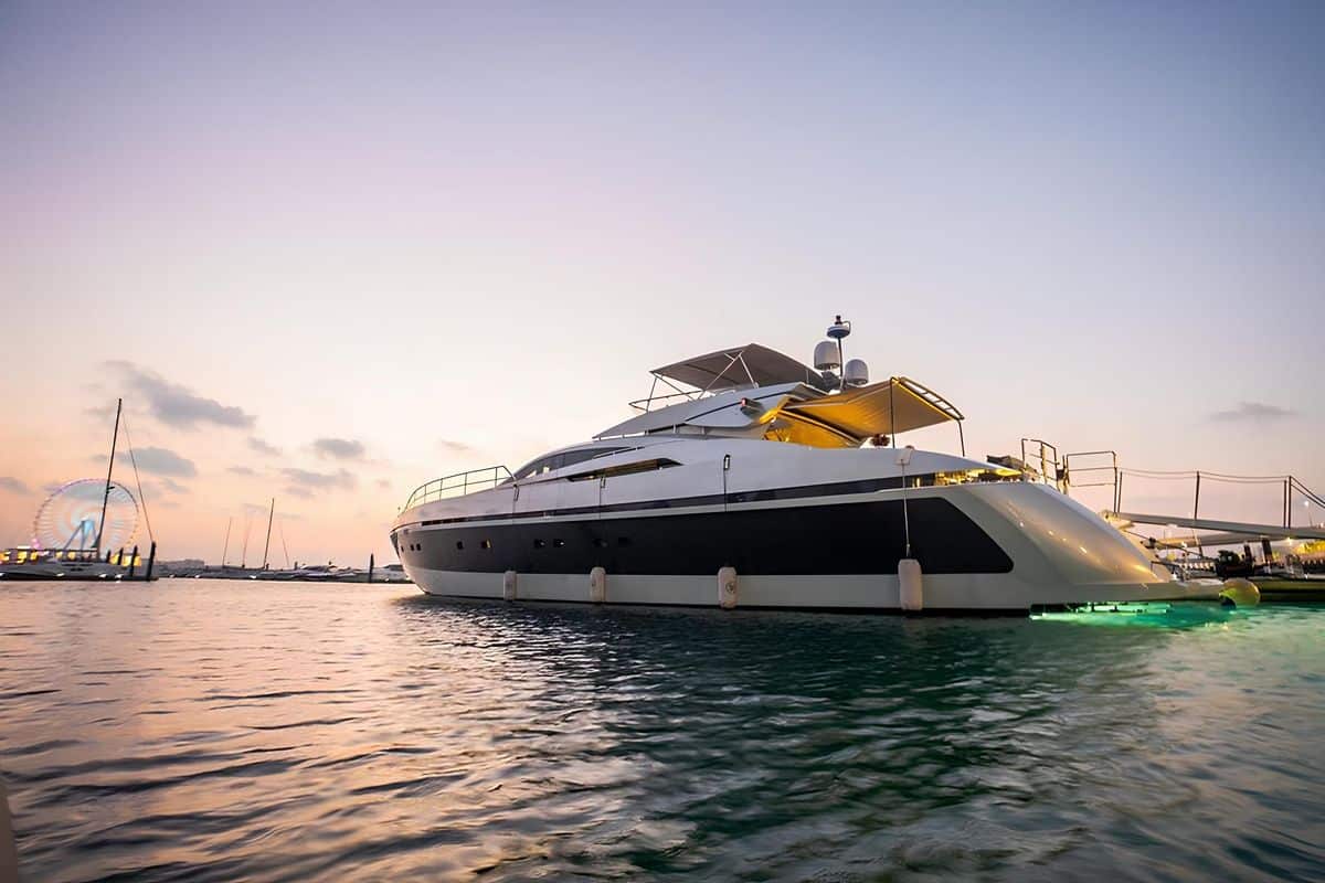 Baglietto 110 yacht front quarter view at sunset with warm reflections on calm sea waters