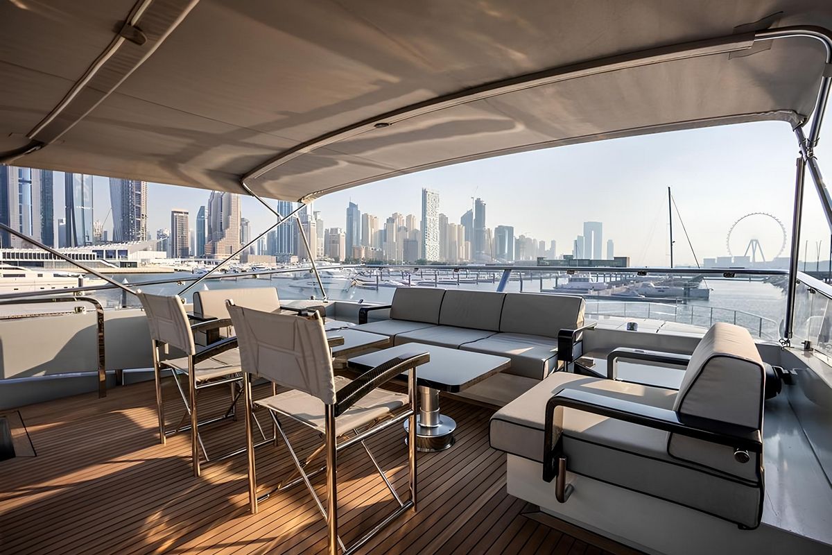Baglietto 110 yacht aft deck dining area with teak flooring, shaded seating and panoramic skyline views