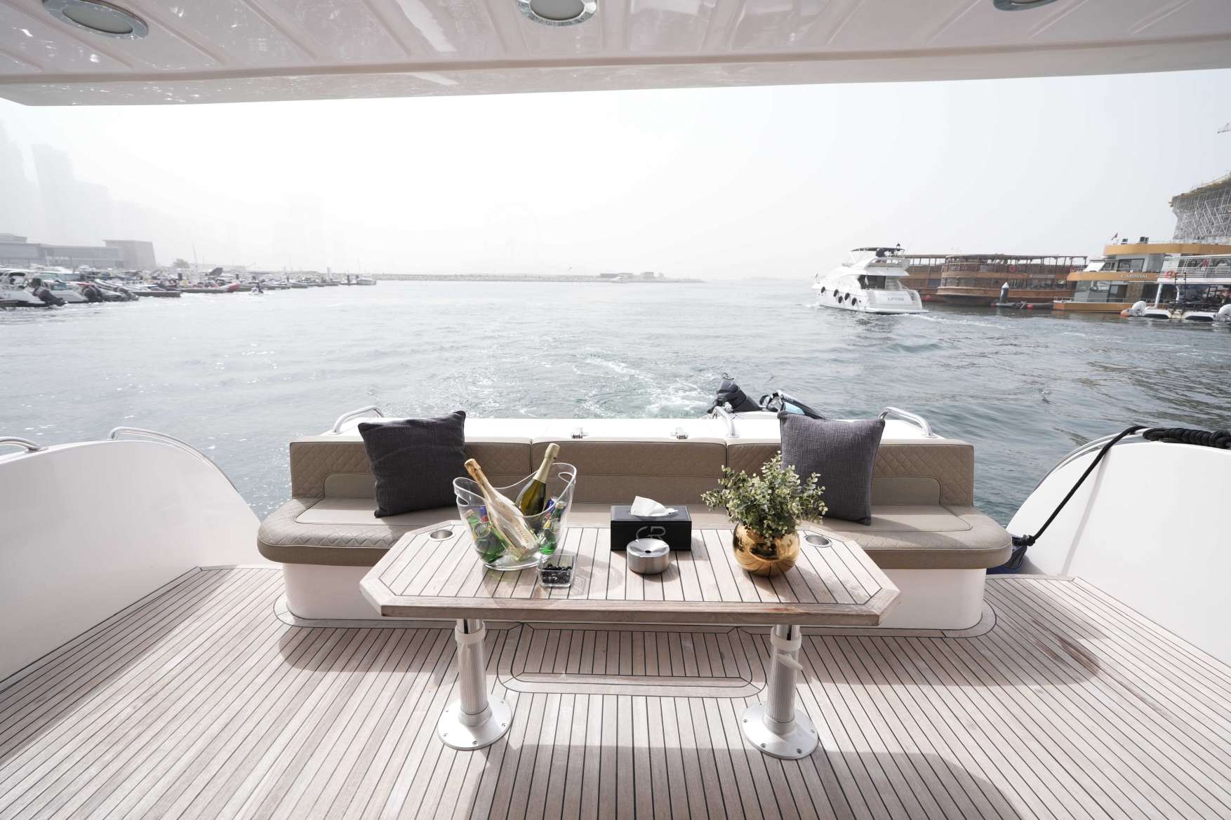Belle 75 luxury yacht rear deck seating area with table and marina water view