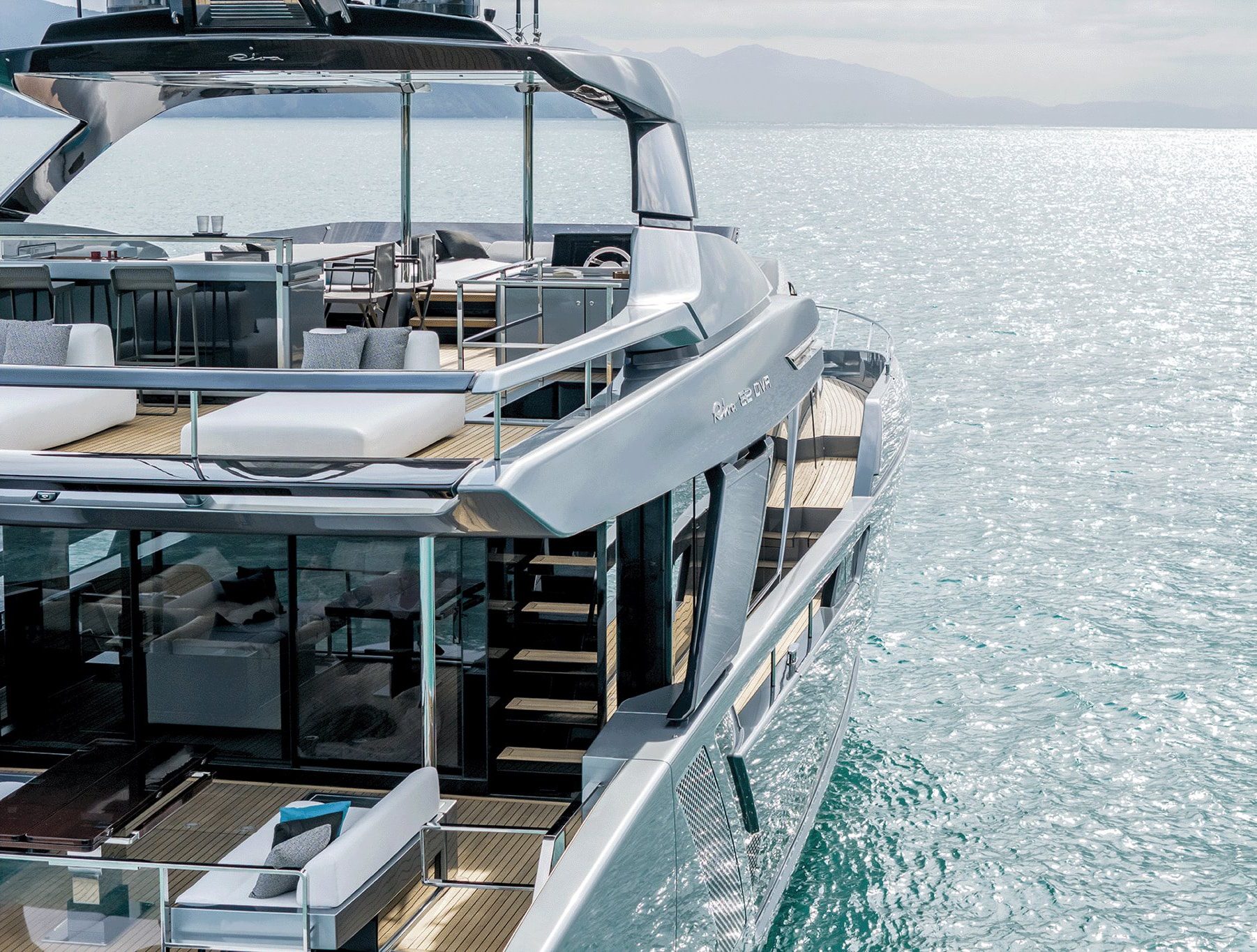 Modern multi-deck luxury yacht with outdoor lounge areas cruising on calm water