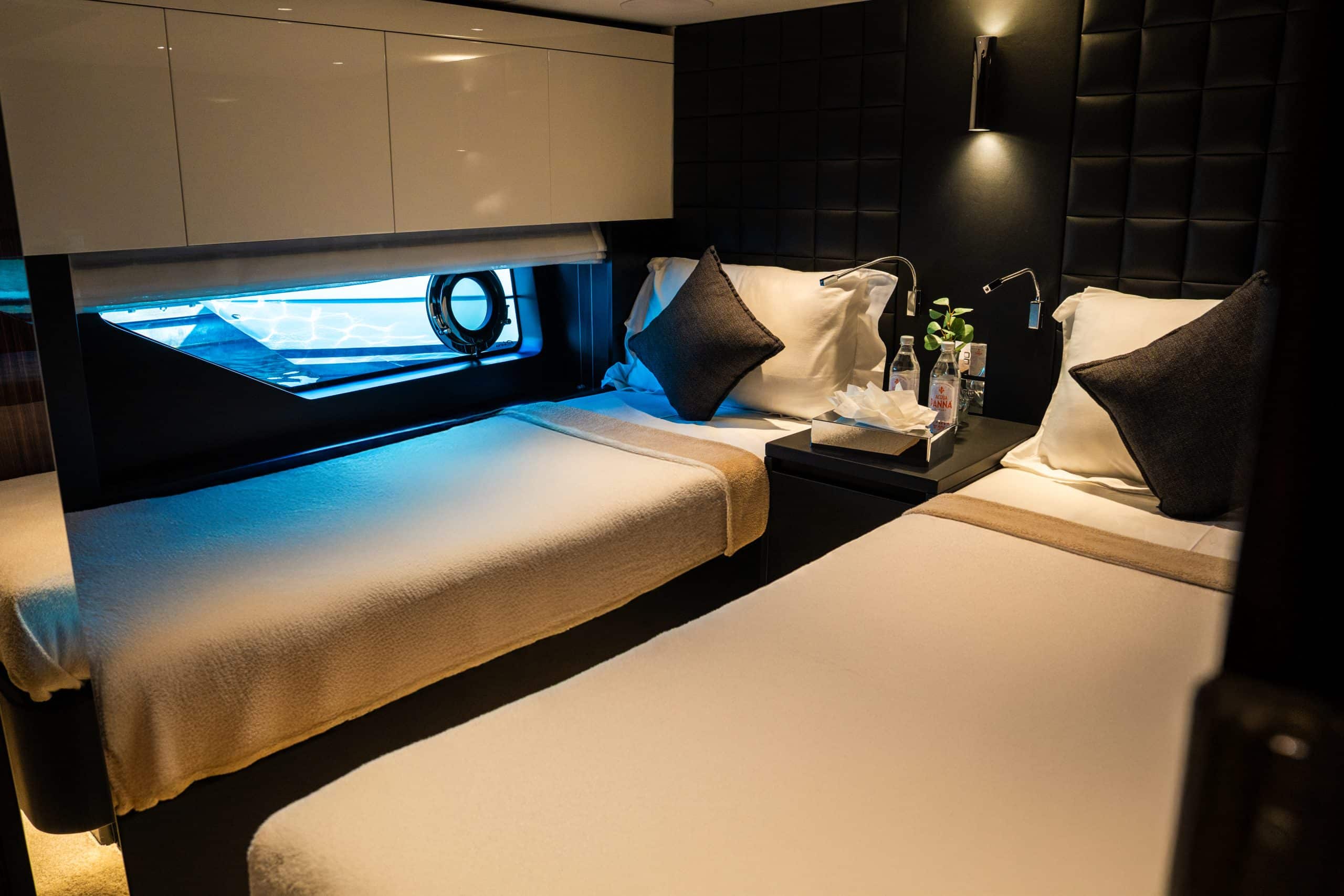 Twin-bed guest cabin with porthole window on a luxury yacht