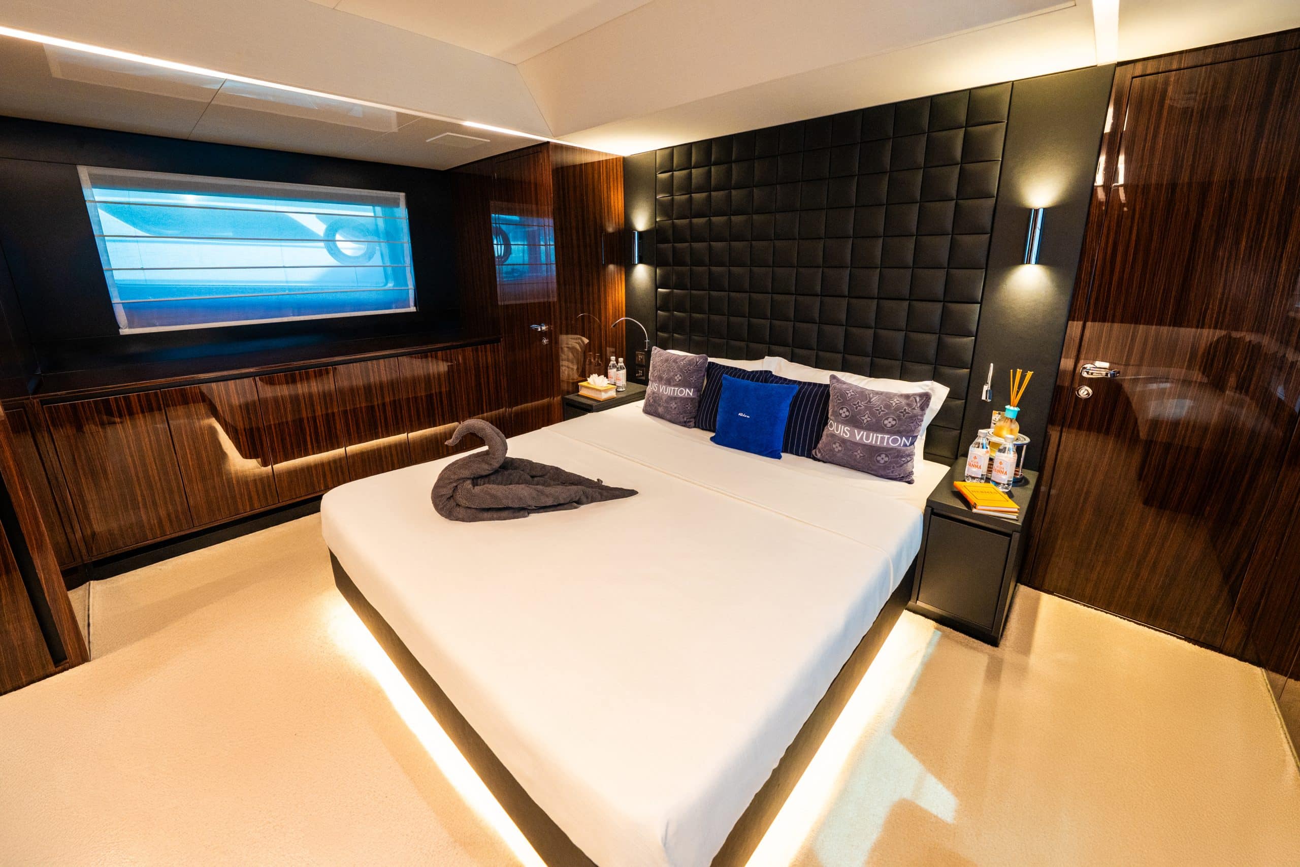 Riva 82 F1 yacht master bedroom with king-size bed, ambient LED lighting, panoramic window, and luxury Italian wood interiors