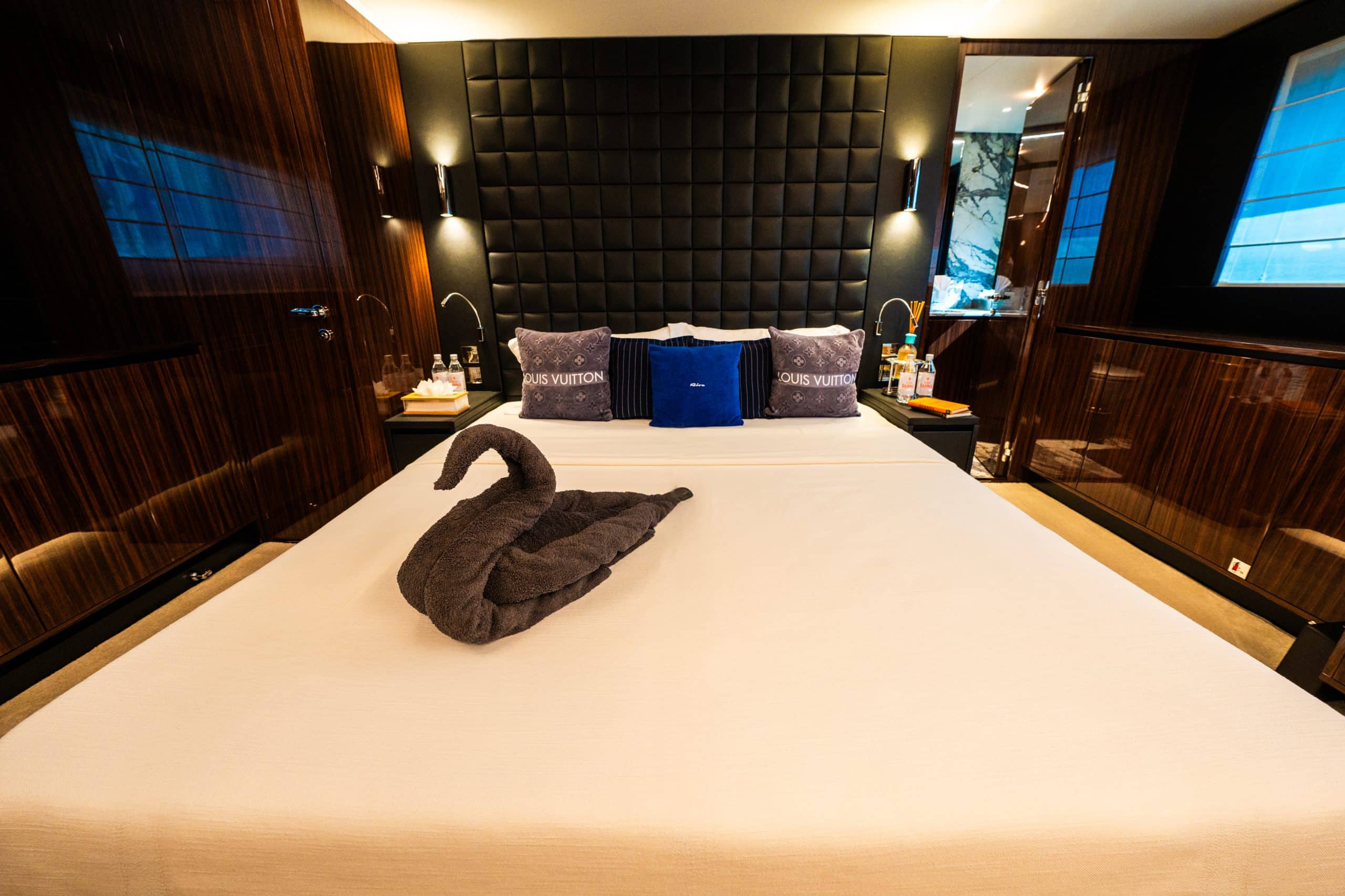 Luxury master cabin interior on Riva 82 F1 yacht with king-size bed, designer décor, padded headboard, and elegant wood panel finishes