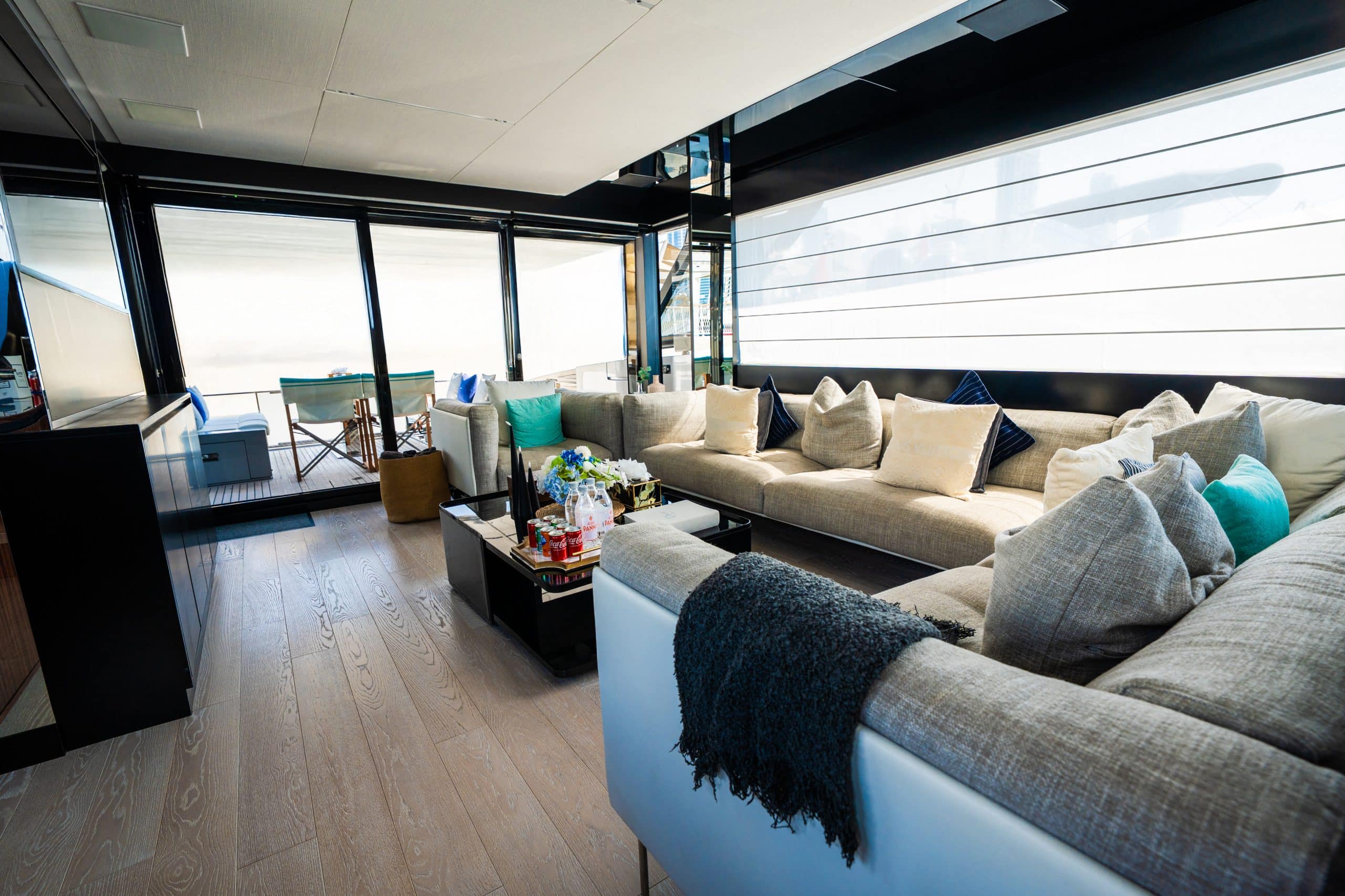 Riva 82 F1 yacht interior lounge with large sectional sofa, modern coffee table, and sliding glass doors to aft deck