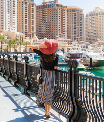 Woman walking along Dubai Marina promenade with yachts and skyline