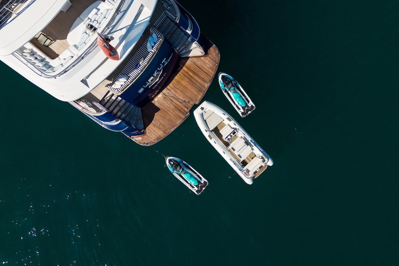 Overhead view of the 54m Baglietto swim platform with three tenders tied alongside in deep green water