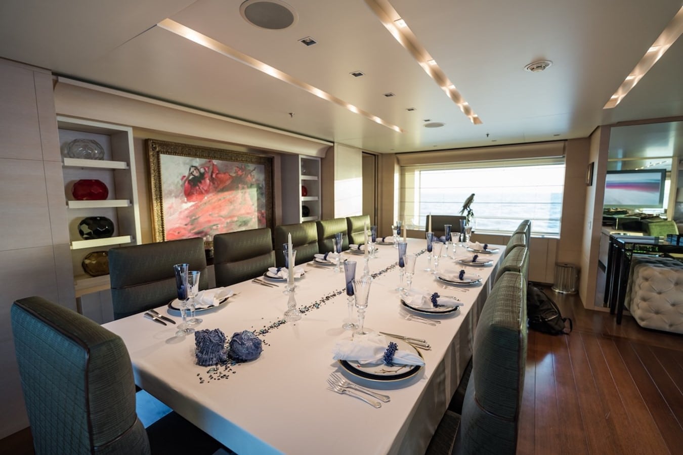 Formal yacht dining room set for ten with crystal glassware, blue napkins and a red abstract artwork