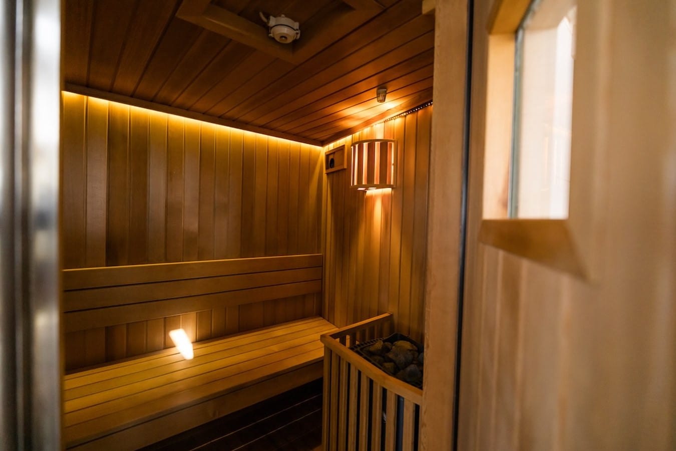 Cedar-lined onboard sauna with warm lighting, bench seating and a stone-filled heater