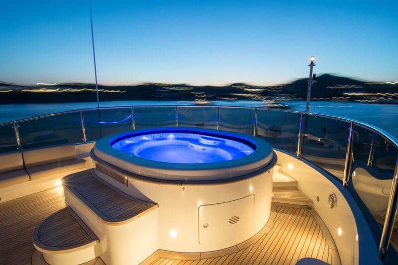 Benetti 56M sundeck jacuzzi lit blue at dusk, mast lights on