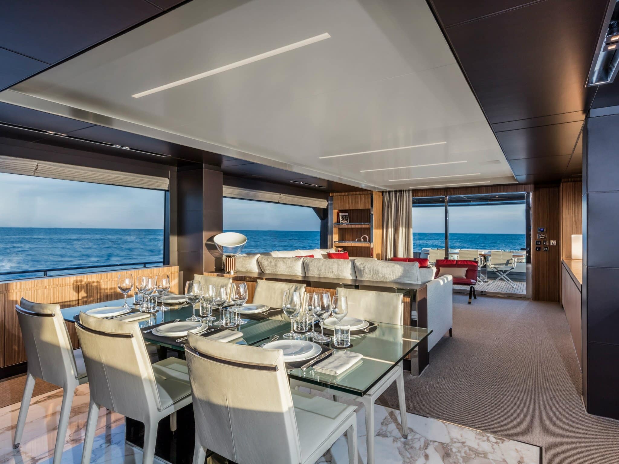 Riva 100 Corsaro main saloon dining table beside full-height glass